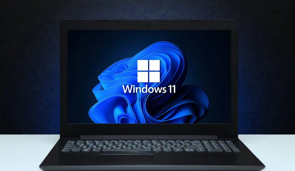 Un computer portatile che mostra il logo di Windows 11 e l'iconico sfondo blu sullo schermo.