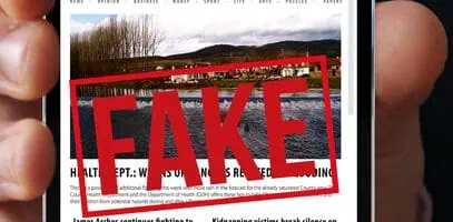 Una persona tiene in mano uno smartphone che mostra un sito web di notizie con la scritta 