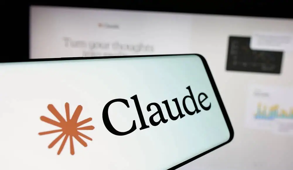 Uno smartphone mostra il logo Claude davanti a uno schermo di computer sfocato con grafici e testo, evidenziando la perfetta integrazione con le funzioni avanzate di intelligenza artificiale di Claude.