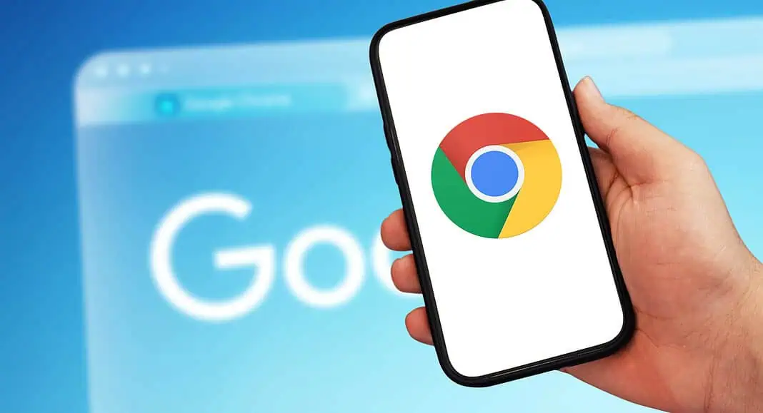 Una mano regge un telefono che mostra il logo di Google Chrome, con una homepage di Google sfocata sullo sfondo, a suggerire l'acquisizione di informazioni senza soluzione di continuità attraverso uno dei browser più diffusi.