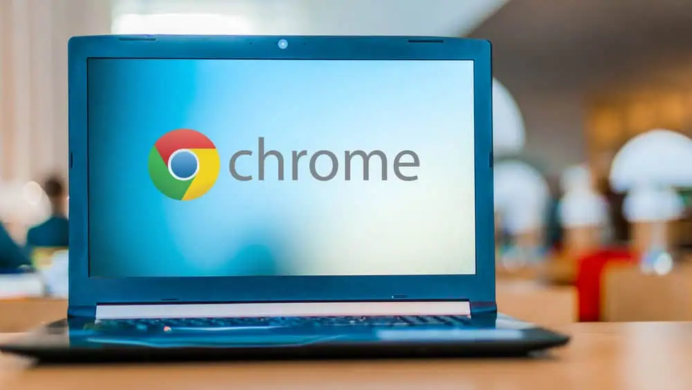 Un computer portatile che mostra il logo e il nome di Chrome sul suo schermo, su uno sfondo interno sfocato.