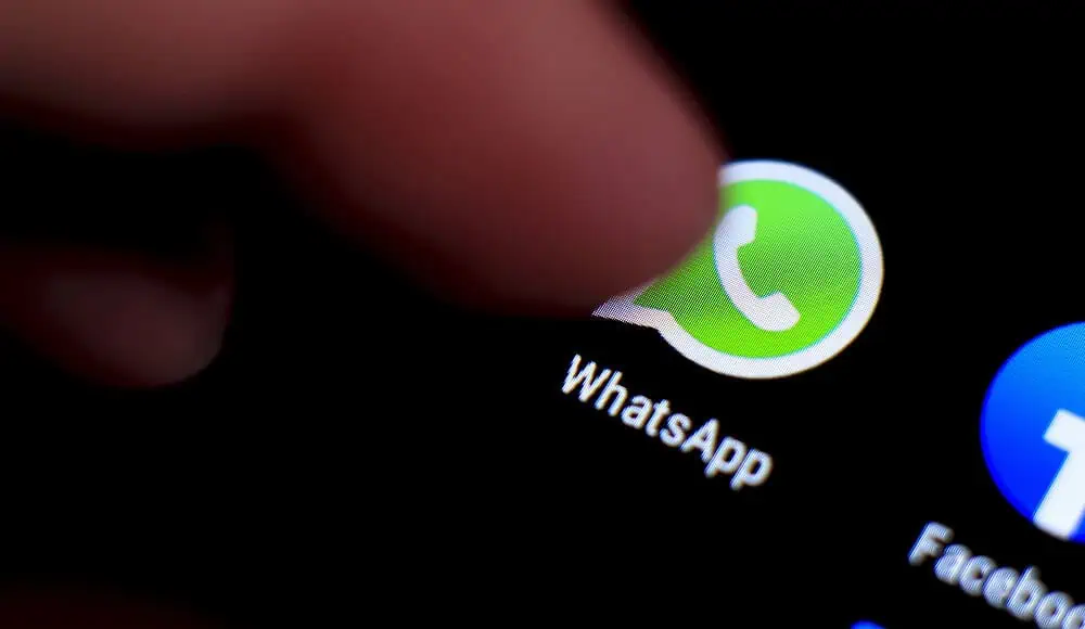 Un dito tocca l'icona dell'app WhatsApp sullo schermo di uno smartphone, pronto a iniziare a chattare all'istante.