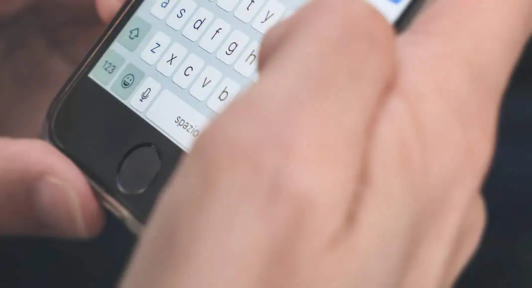 Una persona scrive un messaggio in WhatsApp su uno smartphone, con la tastiera visibile sullo schermo.