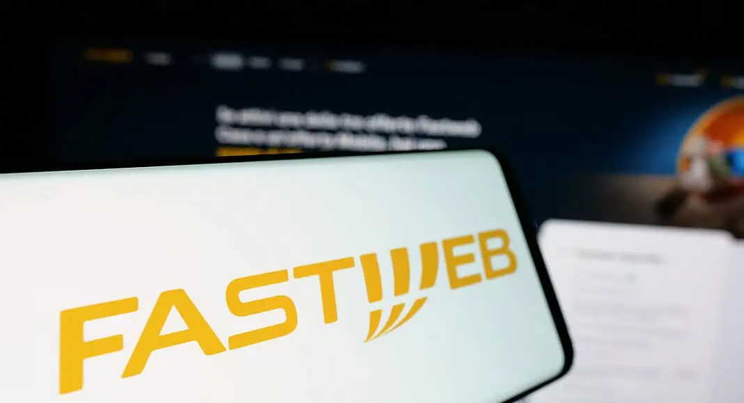 Uno smartphone mostra il logo di Fastweb in giallo, con lo sfondo sfocato del sito web: un'immagine di uno dei principali provider italiani, anche durante un disservizio.