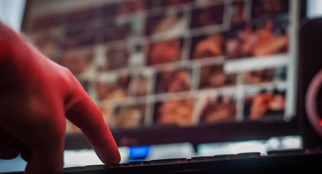 Una mano che digita su una tastiera davanti a uno schermo di computer che visualizza immagini sfocate