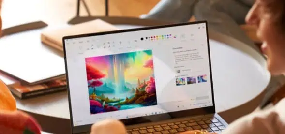 Due persone guardano un paesaggio digitale colorato sullo schermo di un computer portatile, creato con Microsoft Paint.