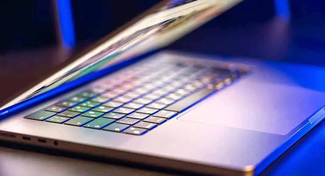 Un computer portatile Windows parzialmente chiuso con tasti illuminati, su uno sfondo scuro con illuminazione blu.