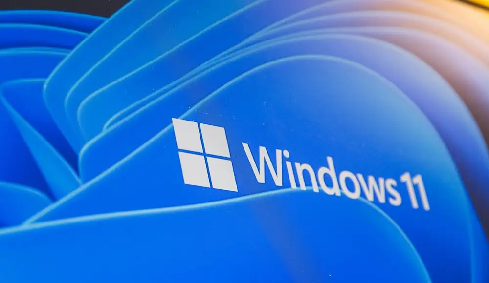 Logo e testo di Windows 11 elegantemente visualizzati su uno sfondo blu e astratto, che cattura la moderna essenza di Windows 11.