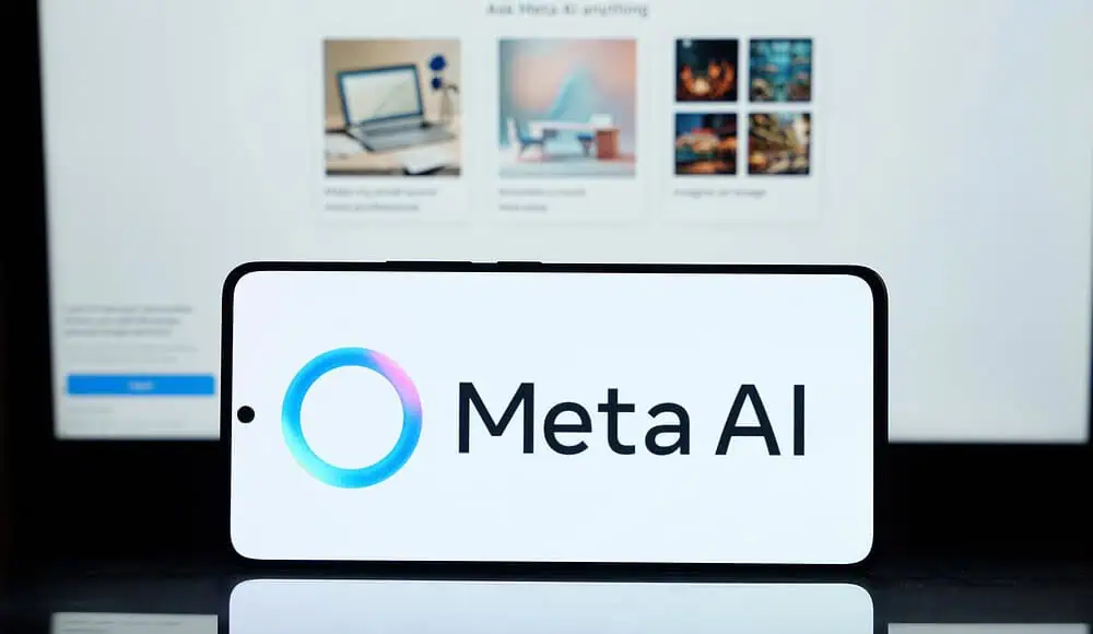 Uno smartphone mostra il logo Meta AI davanti a uno schermo di computer sfocato che mostra immagini e testo di Facebook Marketplace.