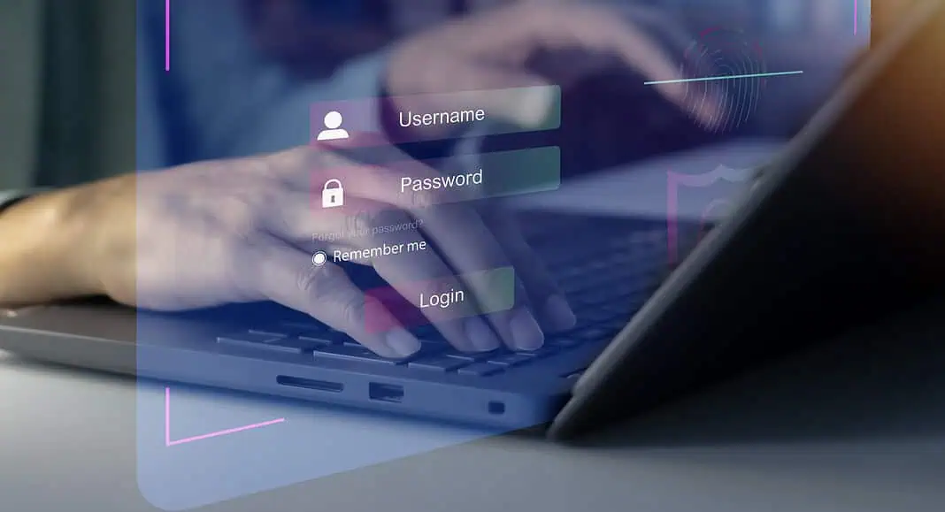 Una persona scrive su un computer portatile con una schermata di accesso digitale che mostra nome utente, password e opzioni di accesso in Microsoft Edge.