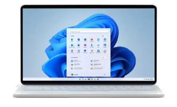 Un computer portatile con il menu di avvio di Windows 11 sullo schermo su uno sfondo chiaro.