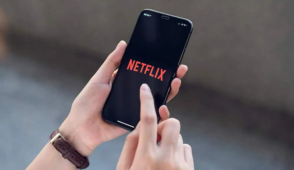 Una persona che tiene in mano un telefono con Netflix aperto sullo schermo, pronta a trasmettere i suoi programmi preferiti.