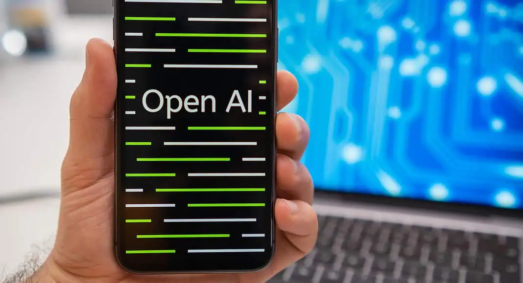 Una mano regge un telefono su cui compare la scritta 