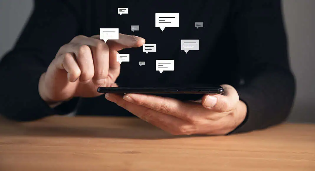 Persona che utilizza uno smartphone con le icone dei messaggi di chat digitali che fluttuano sopra lo schermo, evidenziando il controllo della chat senza soluzione di continuità per una comunicazione senza sforzo.